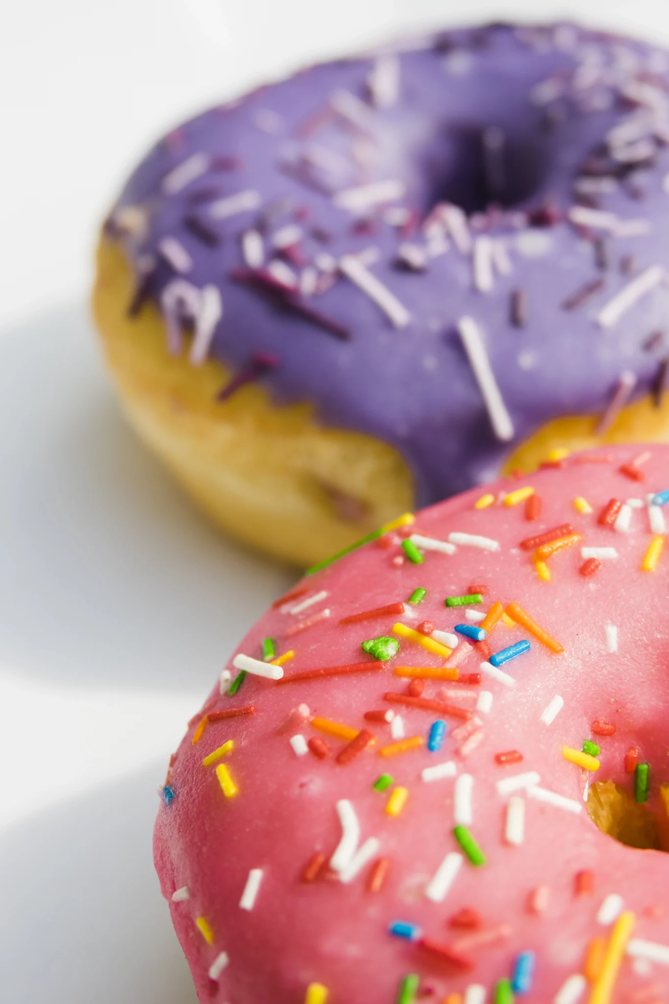pink-purple-donuts-with-colorful-sprinkle-white-backdrop